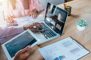 Two mature business people working together in office with digital tablet and calculator and laptop.