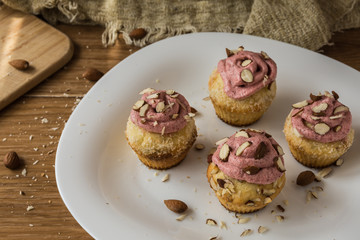 Muffins with strawberry foam and almonds on a white plate
