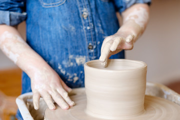 pottery handcraft hobby. little girl forming and shaping clay jug on potter wheel