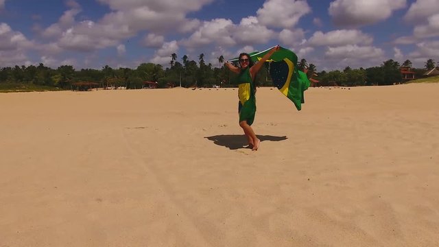 Aerial image of beautiful girl holding the flag of Brazil.