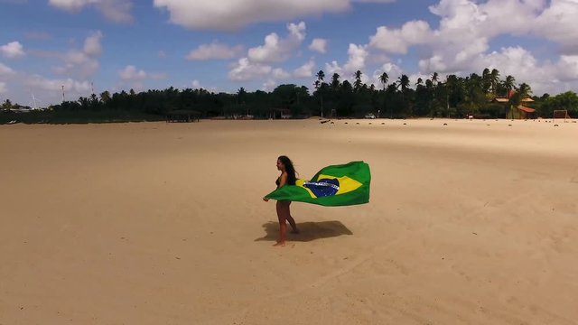 Aerial image of beautiful girl holding the flag of Brazil.