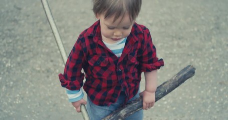 Little toddler boy in nature with two sticks