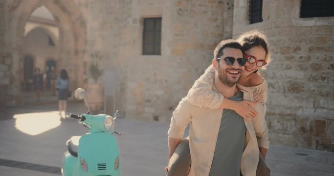 Young tourists couple with scooter having fun with piggyback ride