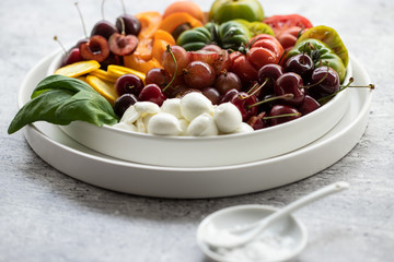 Caprese mit grünen und roten tomaten, kirschen, mozzarella und basilikum