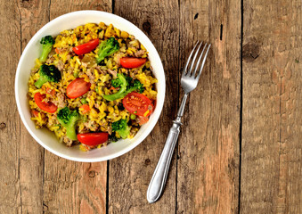 View from above of bowl with tuna risotto with vegetables, tomatoes, broccoli and parsley