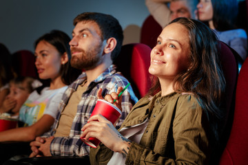 Fototapeta premium Group of friends sitting in movie theater with popcorn and drinks