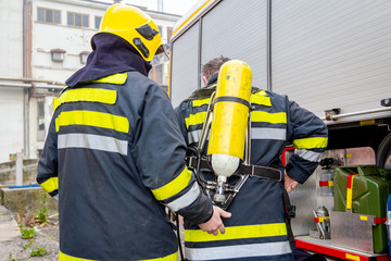 Fototapeta premium Fireman is helping colleague to manage full safety gear