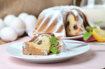 Cut of marble cake sprinkled with sugar, lemon, melissa, milk, eggs and butter
