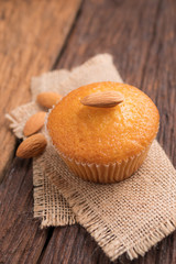 Close up a cup of almond cake against sack fabric on wooden table