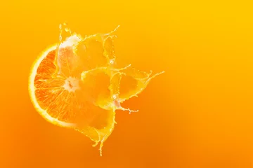  Verse halve plak rijpe sinaasappelfruitflotatie met plonsdruppel op sinaasappelsap met kopieerruimte © Kaikoro