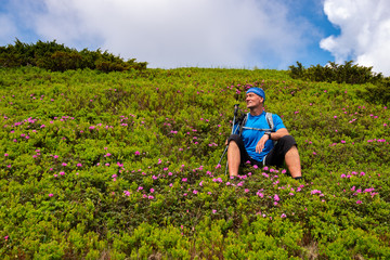 Happy adventurer relaxing on the green mountain slope