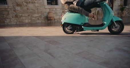Young tourist friends riding vintage scooter in old European city