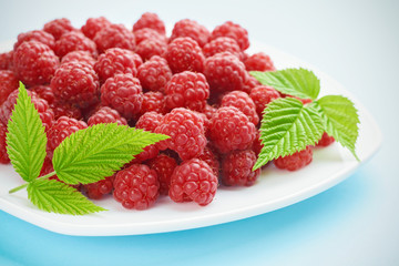 A pile of ripe raspberries on a beautiful blue background