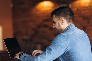 Bearded programmer working on a laptop in a cafe