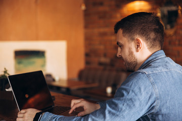Fototapeta na wymiar Bearded programmer working on a laptop in a cafe