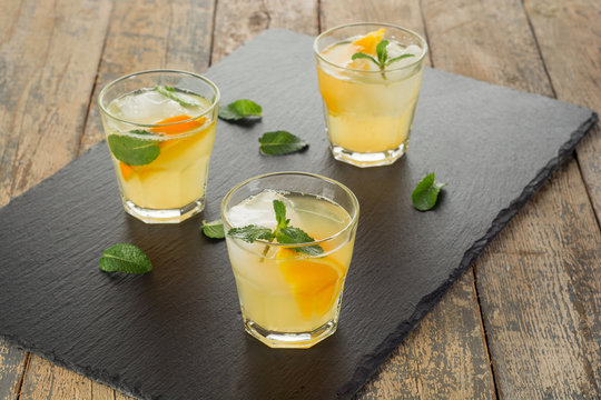Cocktail. Orange juice with mint and ice on rustic wooden table