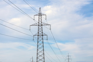 The overhead power line, blue sky and white clouds on the background