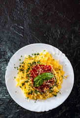 Linguine pasta with fresh tomato sauce, grated cheese and basil in white plate on black background. with copy space. top view
