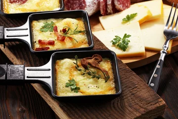 Foto op Aluminium Delicious traditional Swiss melted raclette cheese on diced boiled or baked potato. © beats_