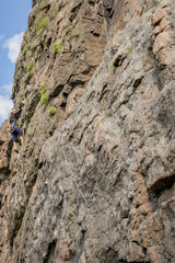 Rock climbing. A young climber climbs a vertical granite rock. Extreme sport.