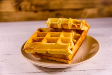 Ceramic plate with belgian waffles on wooden table