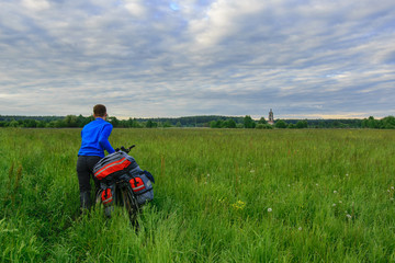 Bicyclist in the field and abandoned church of St. Nicholas near Kirzhach river in Russia