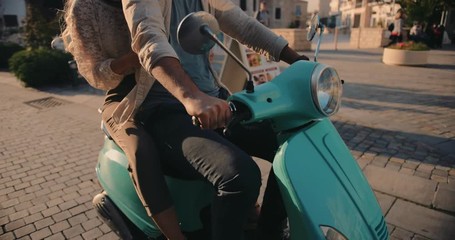 Young couple riding retro motorcycle on cobblestone European city street
