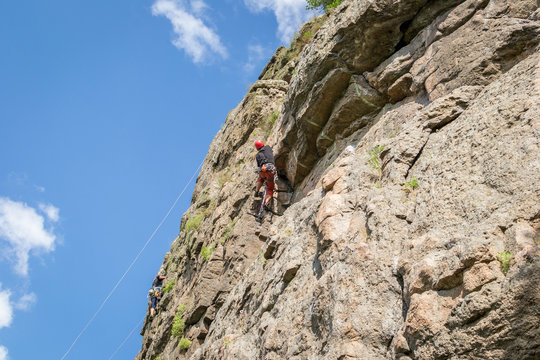 Rock climbing. A young climber climbs a vertical granite rock. Extreme sport.