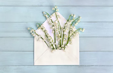 Cercles muraux Muguet Beautiful flowers white lily of the valley ( Convallaria majalis, lily-of-the-valley, May bells, Mary's tears ) in paper postal envelope on background of blue painted wooden planks. Top view, flat lay