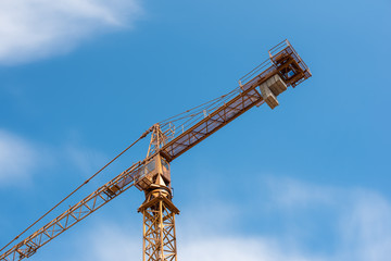Fototapeta na wymiar Yellow construction crane against blue sky with white clouds.