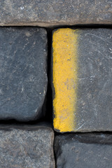 Old road tiles with yellow paint. Street, road details. Vertical background.