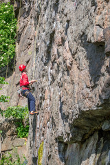 Fototapeta premium Rock climbing. A young climber climbs a vertical granite rock. Extreme sport.