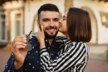 Buying a new home. Happy couple with key to new house. Selective focus on house keys
