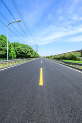 Straight asphalt highway and green forest on a sunny day