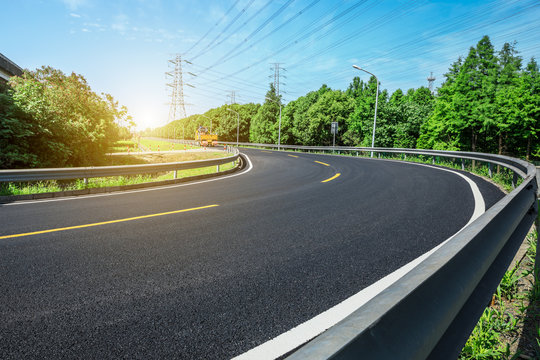 Curved asphalt highway and green forest