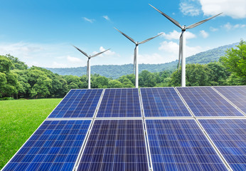 Solar panels and wind turbines in green grass field