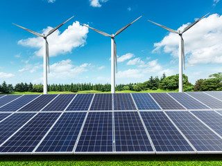 Solar panels and wind turbines in green grass field