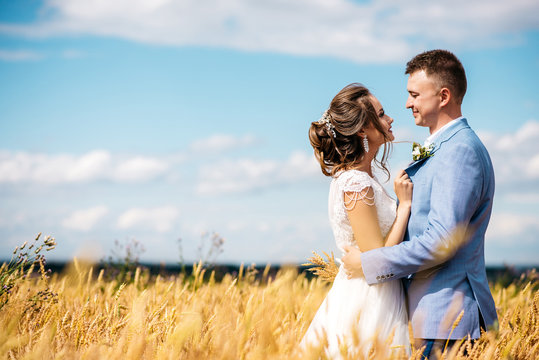 Lovers bride and groom embrace in the middle of a wheat field