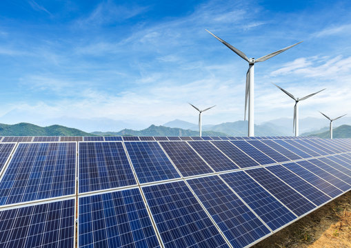 Solar panels and wind turbines with mountains landscape under the blue sky