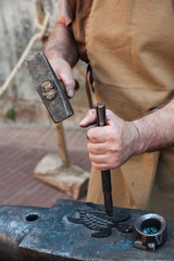 engraving of an iron object with a hammer and chisel.