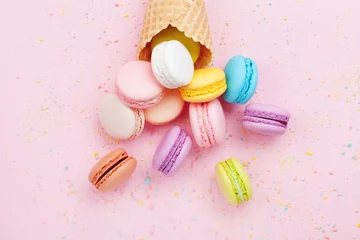 Raamstickers Zoete wafel kegel met macaron of macaroon op roze pastel achtergrond bovenaanzicht. Platliggende compositie. © juliasudnitskaya