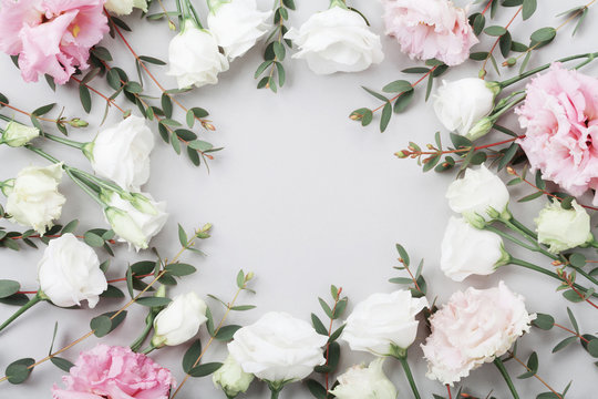 Beautiful floral frame of pastel flowers and green eucalyptus leaves on gray table top view. Flat lay composition.