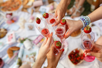 Hands with glasses cheers on summer day picnic
