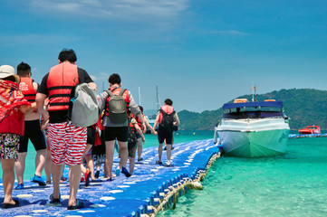 Obraz premium Tourists go by the boat at the pier plastic. Travelers in life jackets sit on board a sea speedboat. Concept activities at the sea