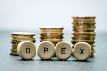 OPEX letter block and stack coins, business concept. OPEX stands for Operational Expenditure.