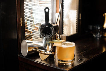 Yellow cocktail and set of essential barman equipment