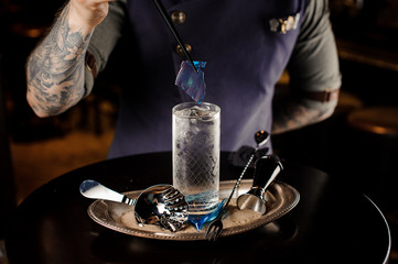 Bartender decorate a cocktail glass with a transparent blue caramel sheet