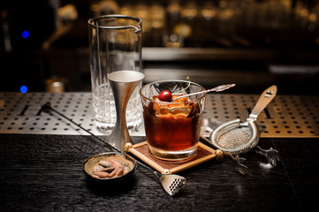 Delicious brown cocktail with ice and cherry