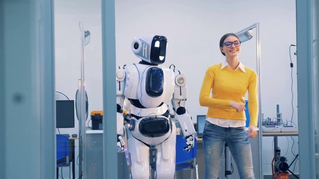 Robot and human relations. A cyborg spanks a woman, while dancing, then she slaps its face and leaves. 4K.