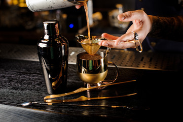 Bartender pouring an alcoholic cocktail into the copper cup